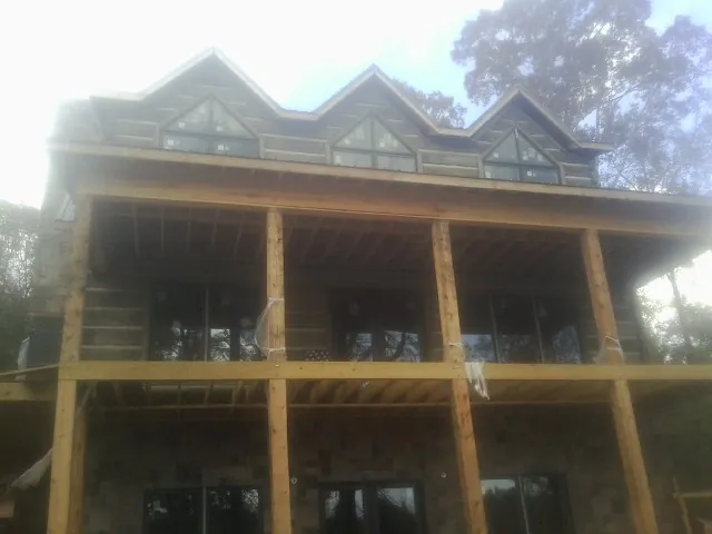 Dormers and porch framing on a large log home under construction — Roof Coating work by our crew in Green Mountain