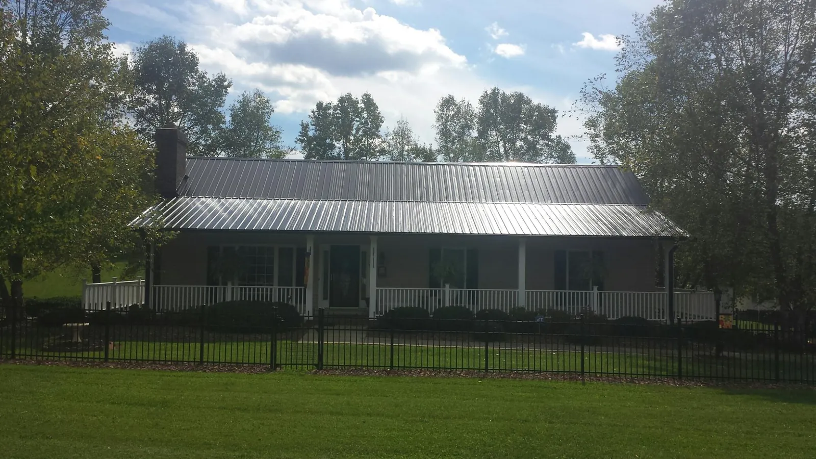 Gray metal roof on a brick ranch with a full width front porch — Gutter Guard Installation work by our crew in Green Mountain