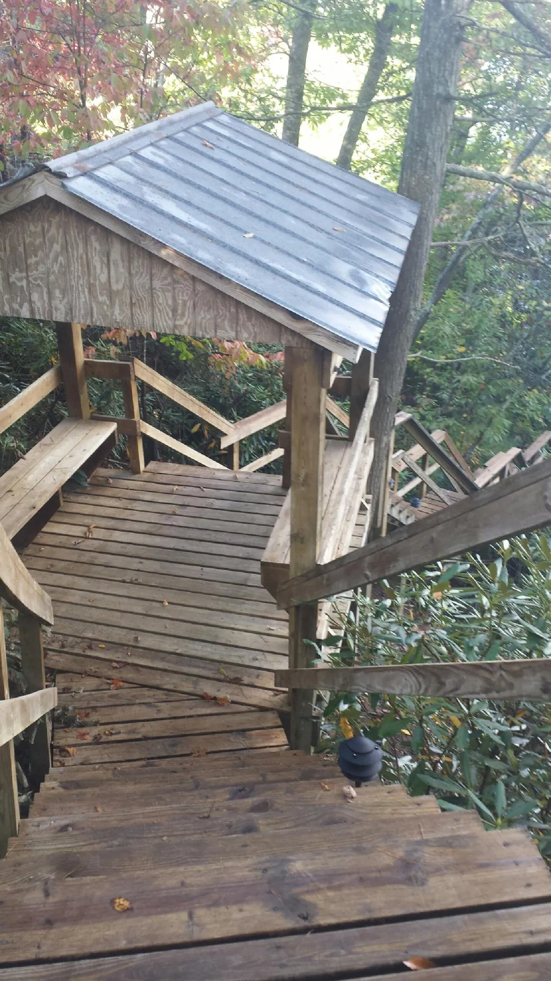 Metal roofed shelter over wooden steps on a wooded walkway — Skylight Repair & Installation work by our crew in Green Mountain