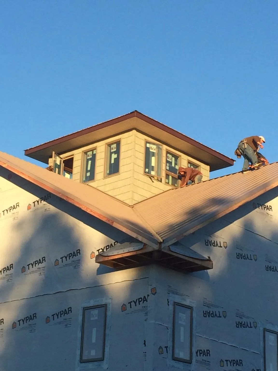 Roofers working around a rooftop cupola on a new metal roof at sunset — Roof Waterproofing in Green Mountain by Roofing Brothers
